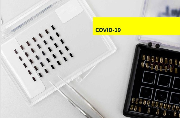 Foto af laboratorie-testkit i nær med skriften "Covid-19" i gult banner ovenpå