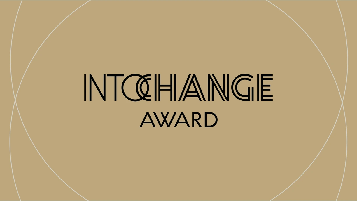Blokbogstaver med "Into change award" skrevet med sort på en baggrund af guld og nogle halvcirkler i tynd hvid streg udenom