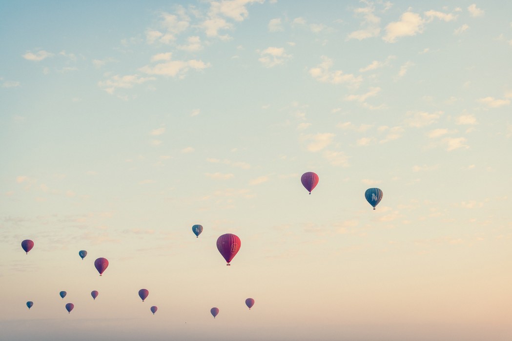 En masse røde og blå luftballoner der flyver på en farverig himmel