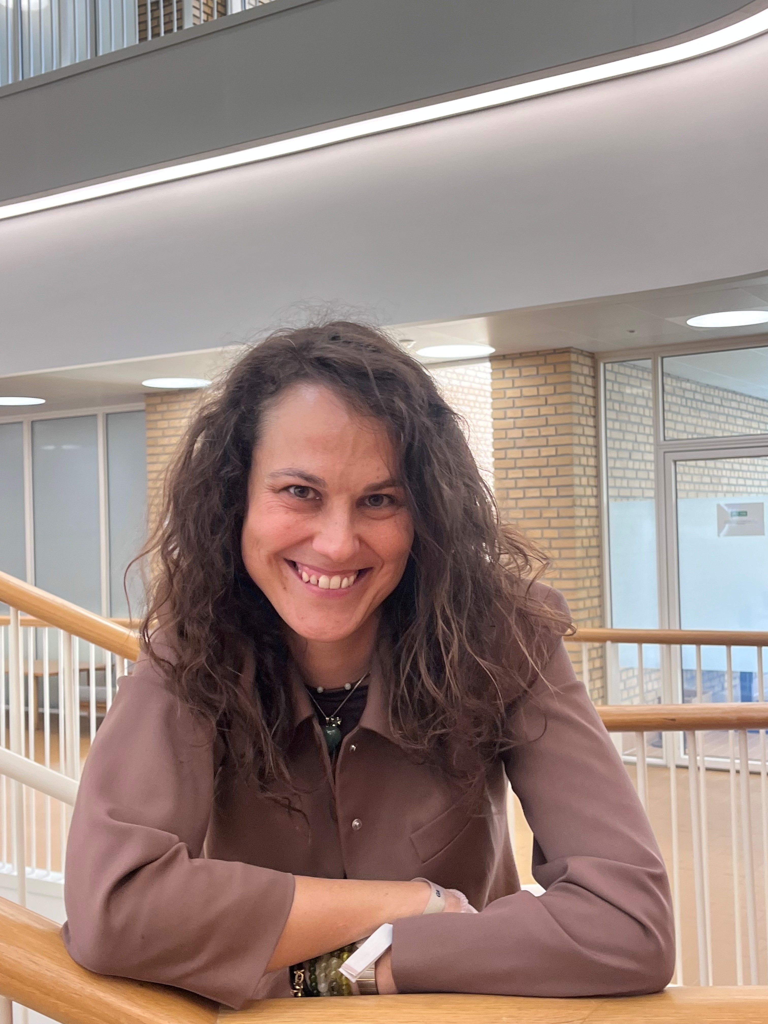 Foto af Anna Mathia Klawonn der smilende læner sig op ad et gelænder på en trappe