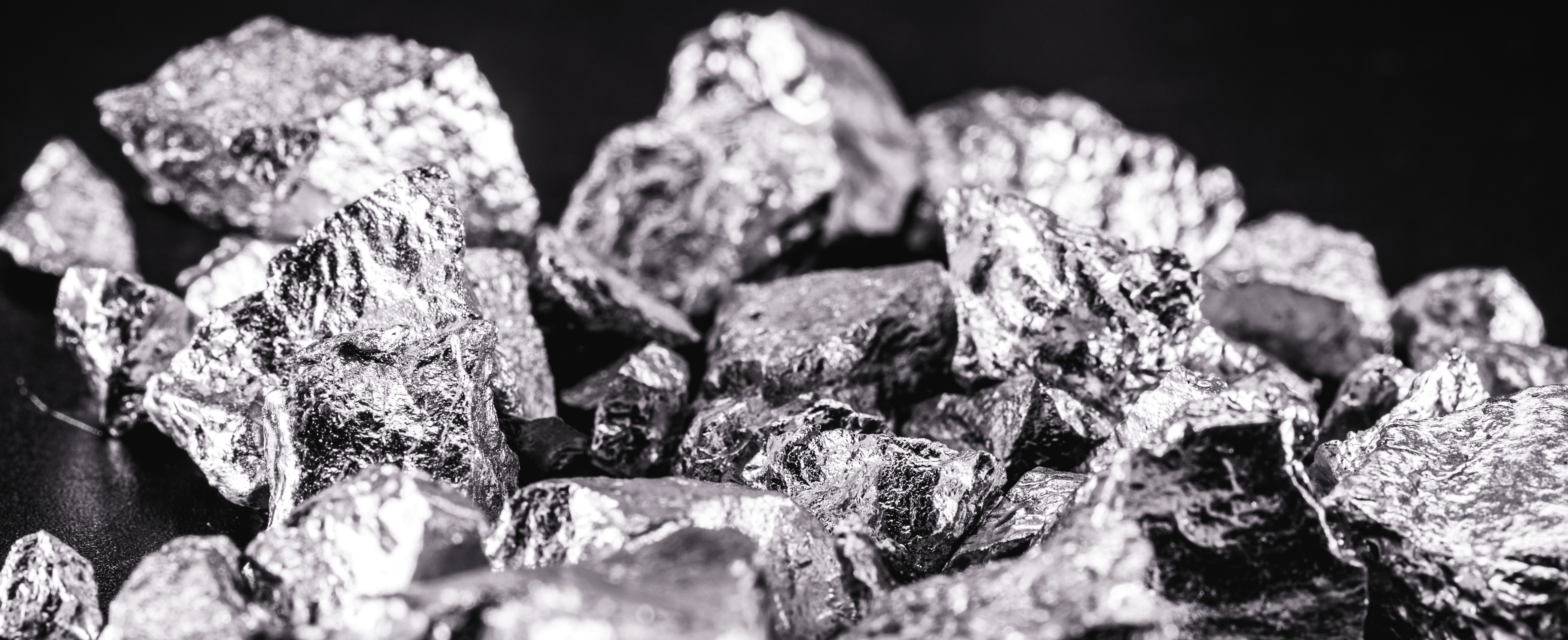 Nærbillede af iridium, som er et sølvlignende metal i klumper på sort baggrund